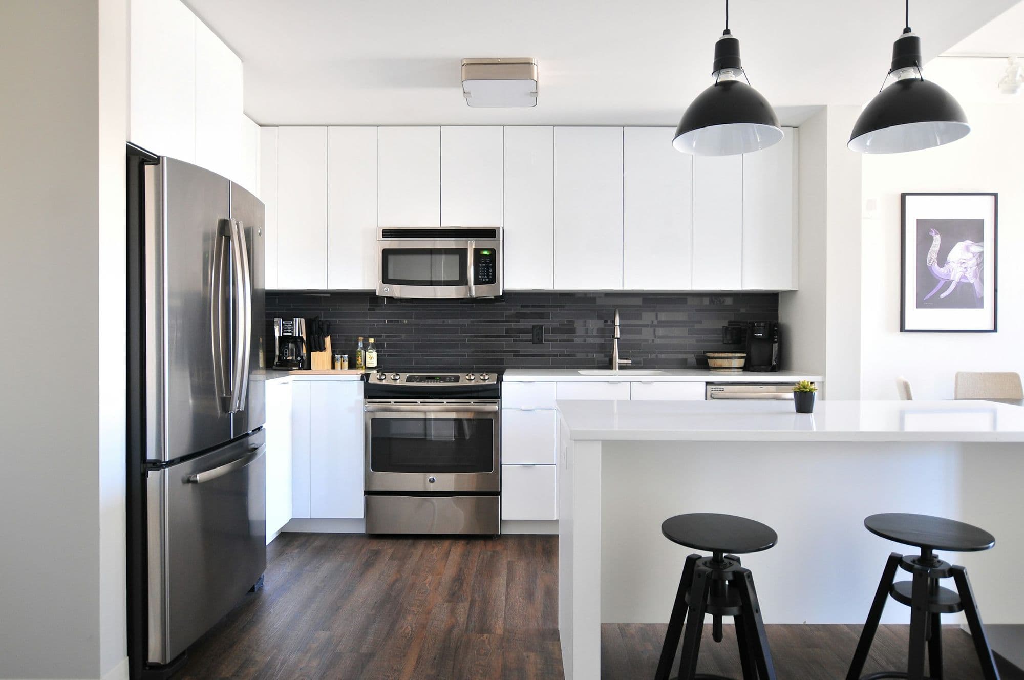 Painted kitchen island with stools beneath two pendant lights